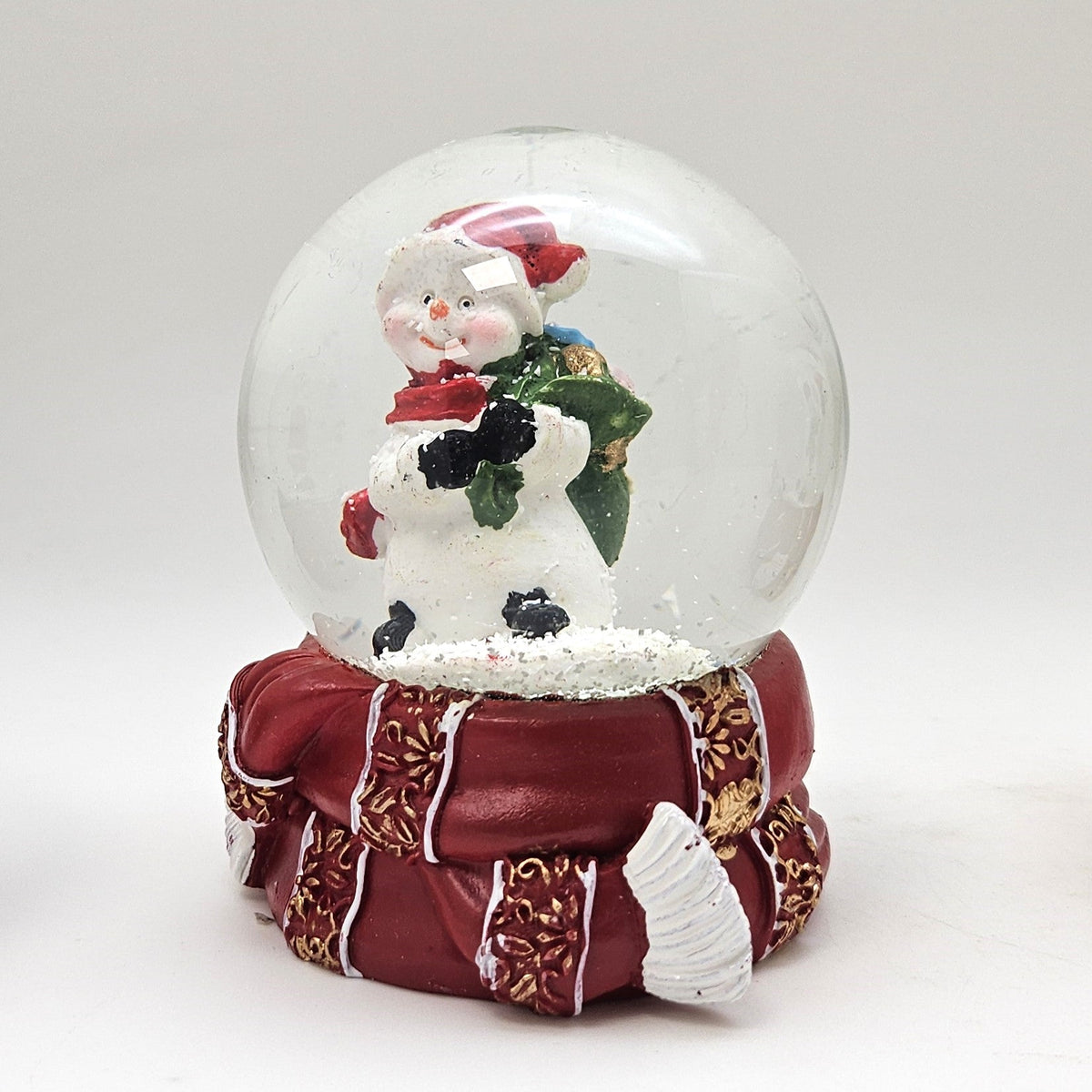 Süße Schneekugel Schneemann grüner Sack auf Sockel rot gold Winterschal B: 65mm - Schneekugelhaus